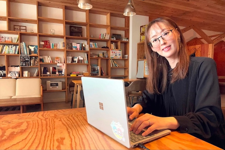 本棚の前の木のテーブルで、さきよさんのノートPCを操作している